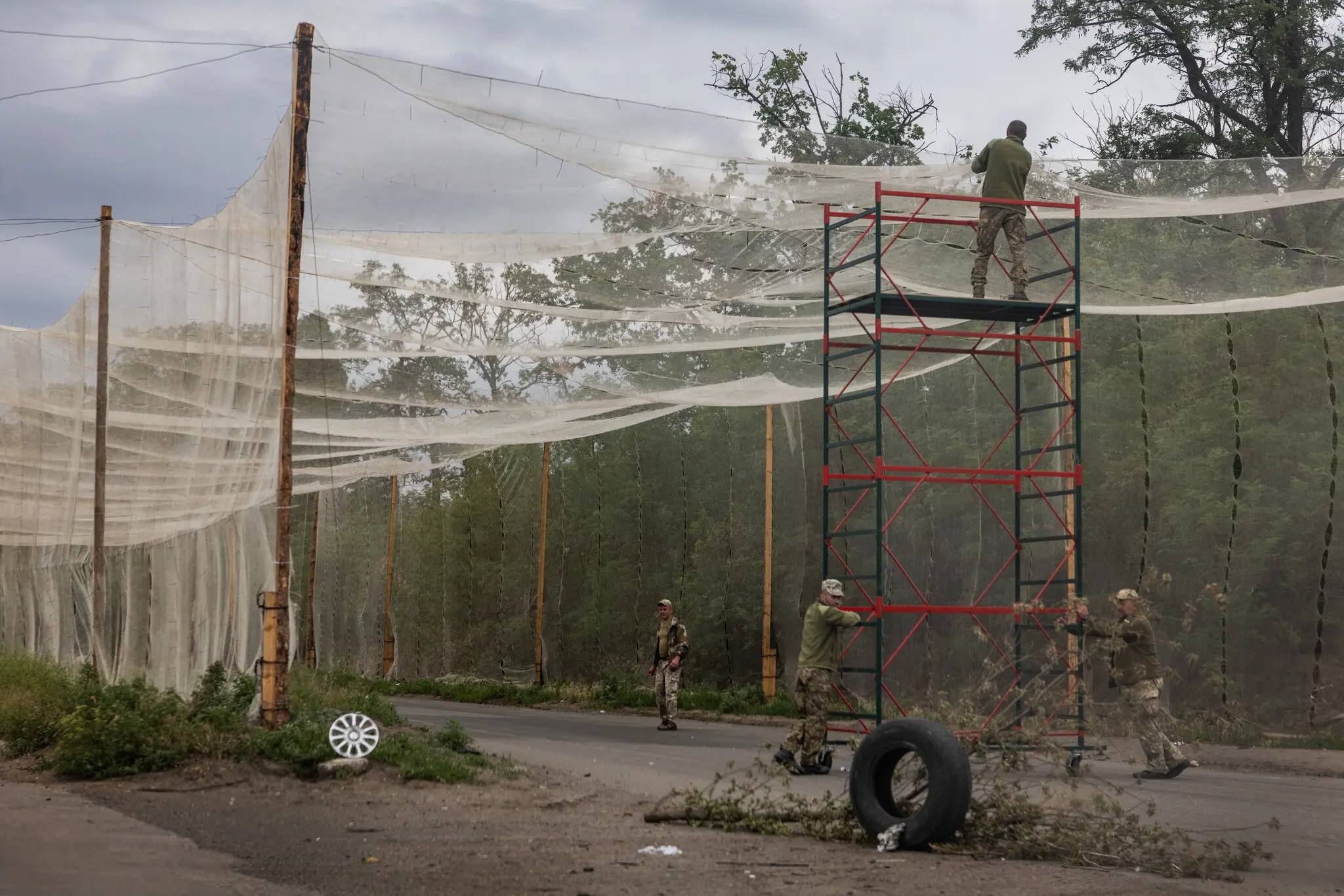 Українські солдати встановлюють сітки над дорогою для захисту від озброєних російських безпілотників у червні вздовж шосе на околиці Костянтинівки.